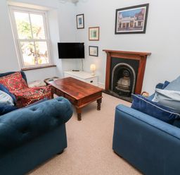 A living room with blue sofas a wooden coffee table a fireplace and a wall mounted TV at Pentira in Kuggar