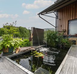 An outdoor water feature with plants and a metal waterfall near a wooden building at Hoarders Cottage in Hay-On-Wye