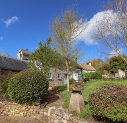 A stone cottage with a garden and trees at Bridge Cottage in Dalwood