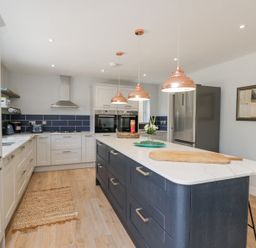 A kitchen with a large island counter and pendant lights at Greystones in Upton St Leonards