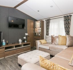 A living room with a beige sectional sofa and patterned curtains at 43 Pony Meadow in Troutbeck Bridge