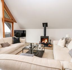 A living room with beige sofas a glass coffee table a fireplace and large windows at Slaley Park Villa in Hexham
