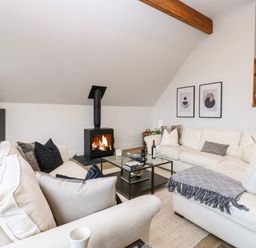 A living room with white sofas black cushions a wood burning stove and glass coffee table at Slaley Park Villa in Hexham