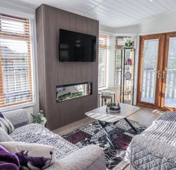 A living room with a television and electric fireplace at JacMar Lodge 14 Applethwaite, Limefitt Park near Windermere