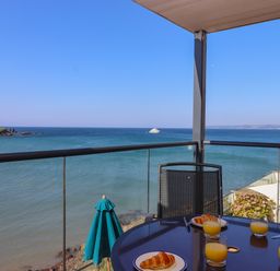 A balcony with a table set with croissants and glasses of orange juice overlooking the ocean at 14 Burgh Island Causeway in Bigbury-On-Sea