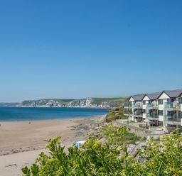 A beach with sand and rocks beside a row of buildings overlooking the sea at 14 Burgh Island Causeway Bigbury-On-Sea