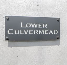 A metal sign with the text Lower Culvermead mounted on a white textured wall at Lower Culvermead in Chaddlehanger near Tavistock