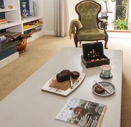 A living room with an armchair and coffee table with cake cup plate game and magazine at Lower Culvermead in Chaddlehanger near Tavistock