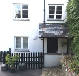 A white two-story house with black picket fence and potted plants at the entrance at Lower Culvermead in Chaddlehanger near Tavistock