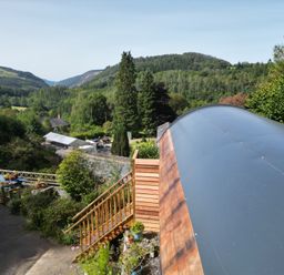 A view of green hills and trees with a wooden staircase and blue picnic table at The Kites Nest in Pont-rhyd-y-groes near Pontrhydfendigaid Snowdonia