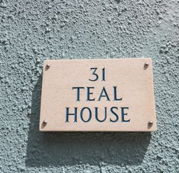 A house number plaque reading 31 teal house on a textured teal wall at Teal House in Lyme Regis