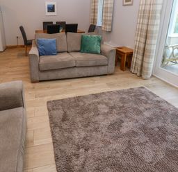 A living room with two sofas a rug and dining table near a window at Primrose Cottage in Goldenbank near Falmouth