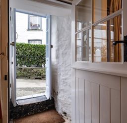An open door leading outside with a small step and a hedge visible at St Samson in Port Isaac