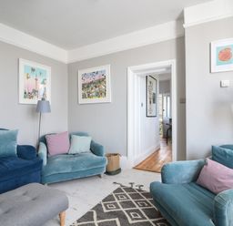 A living room with blue and teal sofas pink and blue cushions floor lamp framed pictures on walls and a patterned rug