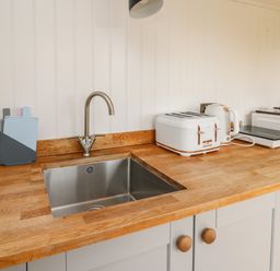 A kitchen countertop with a sink toaster kettle and microwave at Ty Olwyn Bach in Talybont-on-Usk