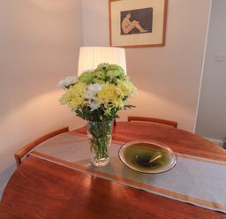 A wooden dining table with a floral centerpiece bowl and table runner with chairs and a framed artwork on the wall at White Feathers in Alnwick