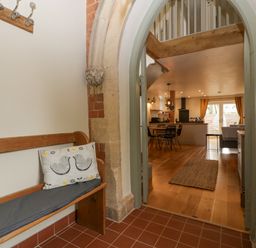 A hallway with a wooden bench and hooks leading to a dining area and kitchen at The Old Chapel in Dorstone near Hay-on-Wye
