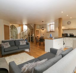 An open plan living area with two gray sofas a dining table and kitchen at The Old Chapel in Dorstone near Hay-on-Wye