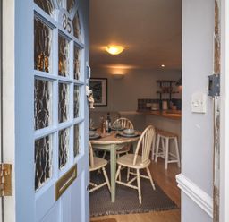 An open blue front door showing a dining area with a table set for four at Braiders Rest in Bridport