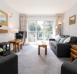 A living room with sofas tables TV and large windows at Fell View in Clappersgate near Ambleside