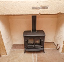 A black wood-burning stove inside a stone fireplace at Victoria House in Alnwick