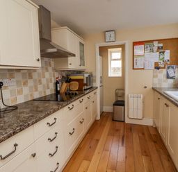 A kitchen with cream cabinets and brown countertops a stove a kettle a microwave a sink and a bulletin board at Victoria House in Alnwick