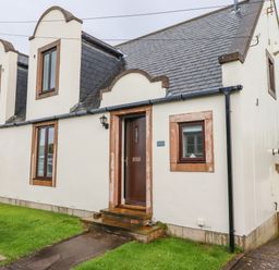 Exterior view of a cream colored cottage with multiple windows and a brown door at Cullernose Cottage Newton-by-the-Sea near Embleton