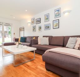 A living room with sectional sofa coffee table and framed pictures on the wall at Garras in Porthtowan