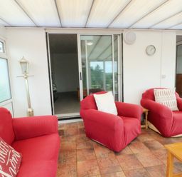 A conservatory with red armchairs and a wooden table at Pen Bonc Llanddaniel Near Gaerwen