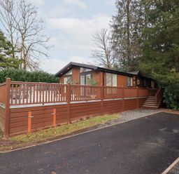 A house with a deck and driveway at Unique Luxury Lodge 1 Langdale, White Cross Bay near Windermere