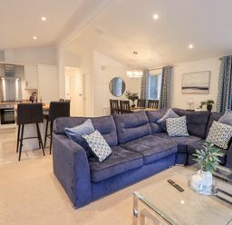 A living room with a sectional sofa and a dining area at Unique Luxury Lodge, 1 Langdale, White Cross Bay near Windermere