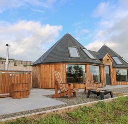 An outdoor area with a hot tub and wooden chairs at Ty Crwn in Lampeter