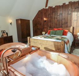A bedroom with a bathtub and a bed at Ty Crwn in Lampeter