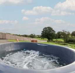 A hot tub with water and trees in the background at Ty Crwn in Lampeter