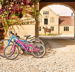 Two bicycles parked against a stone pillar with ivy and an arched stone building in the background at The Stallion in Humshaugh