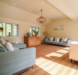 A living room with blue sofas wooden sideboard and wooden floor at Church Farm Barn Dunwich near Westleton