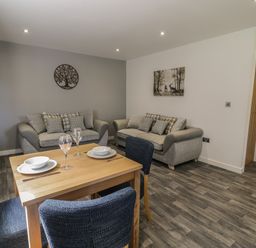 A living room with two sofas a dining table set with plates and glasses at Classic Lodge 16 in Dyserth