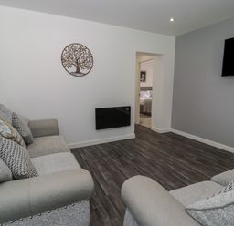 A living room with two sofas with cushions a wall-mounted TV and wall art at Luxury Lodge 69 in Dyserth