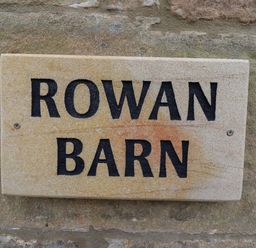 A stone plaque with the text Rowan Barn on a stone wall at Rowan Barn in Bellingham