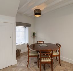 A dining room with a round wooden table and four chairs near a window with a gray blind at Rowan Barn in Bellingham