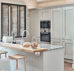A kitchen with a wooden breakfast bar stools oven microwave and countertop appliances at The Hayloft in Humshaugh