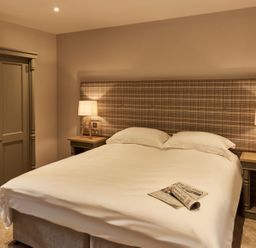 A bedroom with a double bed two bedside tables two lamps and a wardrobe at The Stalls in Humshaugh