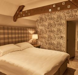 A bedroom with a bed a lamp and an open door showing a bathroom at The Stalls in Humshaugh