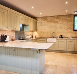 A kitchen with beige cabinets a countertop with a fruit basket coffee machine and a sink at The Carriage House in Humshaugh