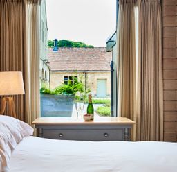 A bedroom with a bed lamp and a wooden table with a bottle and two glasses at The Carriage House in Humshaugh