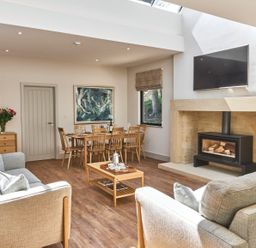 A living room with sofas a dining table a fireplace and a television at The Smithy in Humshaugh