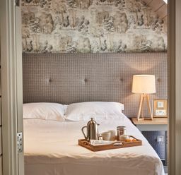 A bed with a tray of coffee mugs and a coffee pot next to a lamp on a bedside table at The Clocktower in Humshaugh