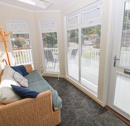 A conservatory with a sofa and coatrack at Serenity in Kilgetty