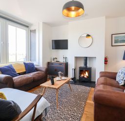 A living room with two brown sofas a wooden coffee table and a wood-burning stove at Long View in Southwold