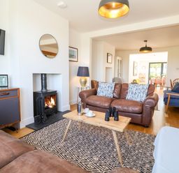 A living room with leather sofas a wood stove and a wooden coffee table at Long View in Southwold
